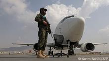 A Taliban fighter stands guard next to an Ariana Afghan Airlines aircraft on the tarmac at the airport in Kabul on September 12, 2021. (Photo by Karim SAHIB / AFP)