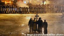 FILE In this file photo taken on Friday, Jan. 24, 2014, Orthodox priests pray as they stand between pro-European Union activists and police lines in central Kiev, Ukraine. As a barricade of blazing tires belched thick black smoke, a line of priests stood between angry protesters and ominous riot police. Every freezing morning, priests sing prayers to demonstrators gathered on the Ukrainian capital's main square, a solemn and soothing interlude to vehement speeches calling for revolution. (AP Photo/Sergei Grits, file)