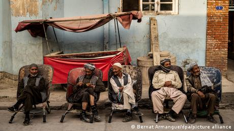 Male day laborers sit at the roadside in Kabul, awaiting a job offer