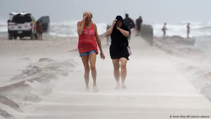 El huracán Nicholas en EE. UU.: dos mujeres caminan cubri¡endose el rostro por la arena que arrastra el viento.