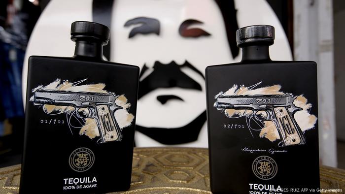 Bottles of the El Chapo 701 brand on display against a backdrop of an image of the drug lord's face