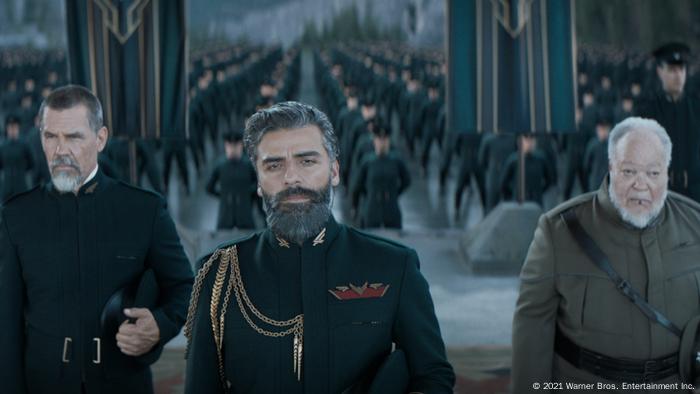 Drei Männer in Uniformen stehen vor mehreren Reihen Soldaten Drei Männer in Uniformen stehen vor mehreren Reihen Soldaten