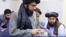 Men are pictured as Afghanistan's Taliban-controlled central bank seizes a large amount of money in cash and gold from former top government officials