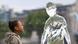 Garota observa estátua de gelo com forma de pessoa derreter Garota observa estátua de gelo com forma de pessoa derreter