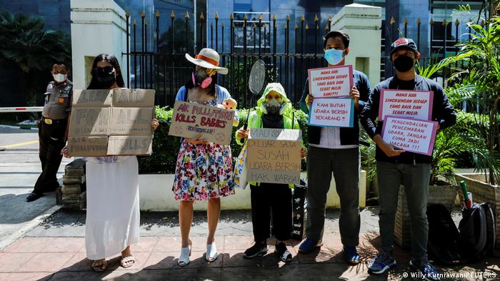 protesters in Jakarta stand in a line outside the courthouse holding signs about the climate