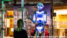 26 October 2018, North Rhine-Westphalia, Paderborn: Curator Judith Spickermann stands in front of the robot robothespian in the exhibition Artificial Intelligence and Robotics at the Heinz Nixdorf MuseumsForum. From 27 October, the Heinz Nixdorf MuseumsForum will be showing the latest developments in artificial intelligence and robotics on 500 square metres. A special highlight of the new department in the permanent exhibition is the sweeping robot Beppo, an industrial robot that performs its artistically inspired work in response to visitors. Photo: Guido Kirchner/dpa
