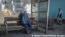 A burqa-clad woman waits for transportation at a bus stop