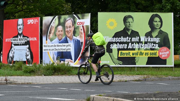 Ein Radfahrer fährt an großen Wahlplakaten der SPD, CDU und den Grünen