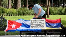 A Cuban man arranges a Cuban flag next to a Venezuelan national flag during a small demonstration in Alameda Park against the participation of Venezuela’s President Nicolas Maduro in the Community of Latin American and Caribbean States, CELAC, summit in Mexico City, Saturday, Sept. 18, 2021. CELAC has only existed for 10 years and is more left-leaning, having remained on good terms with countries including Cuba, Venezuela and Nicaragua. (AP Photo/Ginnette Riquelme)