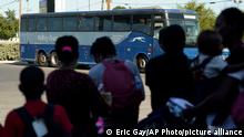 Foto simbólica de personas migrantes que esperan abordar un bus.