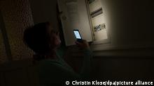 ILLUSTRATION - Eine junge Frau schaut am 29.01.2020 in einer Wohnung in Wittenberge waehrend eines Stromausfalls mit Hilfe der Taschenlampe auf ihrem Smartphone in den Sicherungskasten (gestellte Szene). Foto: Christin Klose