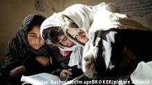 Drei Mädchen arbeiten mit einem Schulbuch, Potokh Primary School, Potokh, Wakhan-Korridor, Afghanistan, Asien