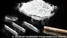 Häufchen von Kokain auf einer Glasplatte und ein gerollter Geldschein, um das Kokain durch die Nase zu ziehen. 