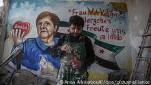 Aziz Al-Asmar, ein syrischer Maler aus Binnish, steht vor seinem Wandgemälde in einem beschädigten Gebäude, das die deutsche Bundeskanzlerin Angela Merkel darstellt. Darauf ist auch die Aufschrift «Frau Merkel Ihr Wohlergehen freute uns in Idilib» zu lesen. Merkel hatte sich am Sonntagabend (22.03.2020) in häusliche Quarantäne begeben, nachdem sie darüber unterrichtet worden war, dass sie am Freitag (20.03.2020) zu einem Arzt Kontakt hatte, der mittlerweile positiv auf das Coronavirus getestet wurde. Bei einem zweiten Test auf das neuartige Coronavirus sei bei Merkel keine Infektion festgestellt worden, teilte ein Regierungssprecher am Mittwoch (25.03.2020) in Berlin mit.