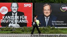 Eine Frau geht an großen Wahlplakaten mit den Spitzenkandidaten Olaf Scholz (SPD, l) und Armin Laschet (CDU) vorbei (Aufnahme mit längerer Verschlusszeit). Am 26. September 2021 entscheiden die Wählerinnen und Wähler über den neuen Bundestag.