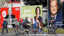 FILE - In this Thursday, Sept. 23, 2021 file photo, People walk and drive past election posters of the three candidates for German chancellor , from right, Armin Laschet, Christian Democratic Union (CDU), Annalena Baerbock, German Green party (Die Gruenen) and Olaf Scholz, Social Democratic Party (SPD), at a street in Gelsenkirchen, Germany. Germany’s closely fought election on Sunday will set the direction of the European Union’s most populous country after 16 years under Angela Merkel, whose party is scrambling to avoid defeat by its center-left rivals after a rollercoaster campaign. (AP Photo/Martin Meissner, File)