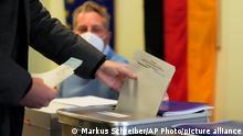 A man casts his vote for Germany's national parliament election at a polling station in Berlin, Germany, Sunday, Sept. 26, 2021. German voters are choosing a new parliament in an election that will determine who succeeds Chancellor Angela Merkel after her 16 years at the helm of Europe's biggest economy. (AP Photo/Markus Schreiber)
