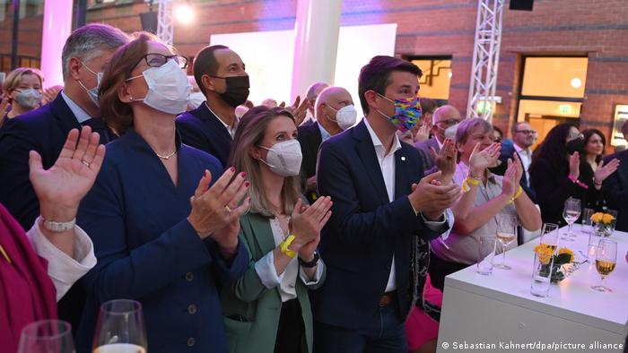 Election party at FDP headquarters: People in masks and not in maskes watching the results on TV and clapping