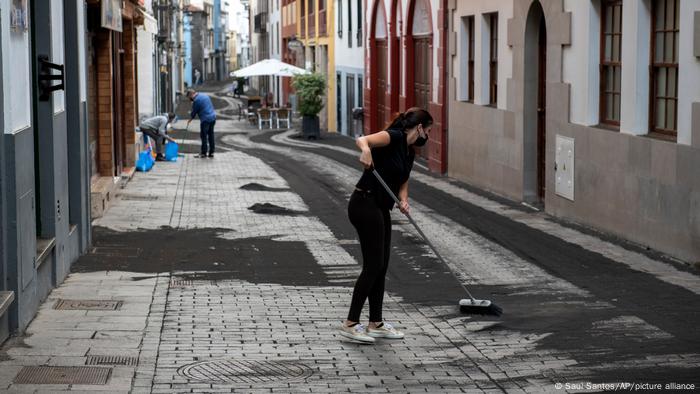 La Palma residents clean the ash from the streets with brooms