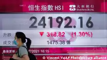 A woman wearing a face mask walks past a bank's electronic board showing the Hong Kong share index at Hong Kong Stock Exchange in Hong Kong Monday, Sept. 27, 2021. Asian share rose Monday, but skepticism about the economic outlook for the region tempered the rally amid worries about further waves of COVID-19 outbreaks. (AP Photo/Vincent Yu)
