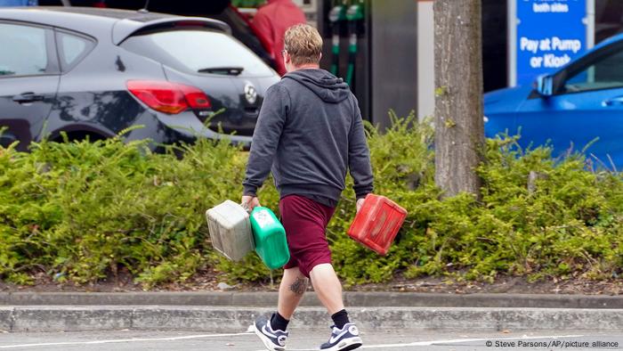A man carries three canisters on his way to a gas station in Bracknell, UK.