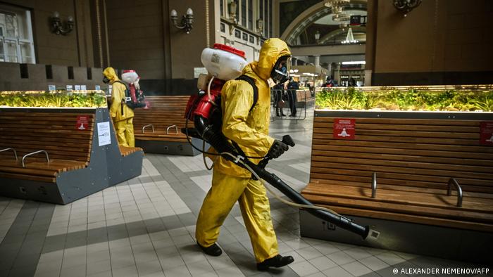 Zwei Reinigungskräfte im Schutzanzug desinfizieren den Wartebereich eines Bahnhofs in Moskau