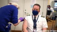 CHICAGO, ILLINOIS - MARCH 09: United Airlines pilot Steve Lindland receives a COVID-19 vaccine from RN Sandra Manella at United's onsite clinic at O'Hare International Airport on March 09, 2021 in Chicago, Illinois. United has been vaccinating about 250 of their O'Hare employees at the clinic each day for the past several days. (Photo by Scott Olson/Getty Images) 