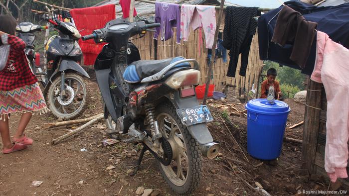 Three motorcycles are parked next to a clothesline in a refugee camp Three motorcycles are parked next to a clothesline in a refugee camp