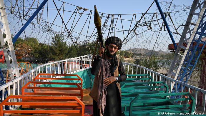 Man carrying a rocked-propelled grenade standing on a pirate ship ride at Qargha Lake on the outskirts of Kabul