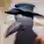 The figure of a plague doctor wearing a beaked mask