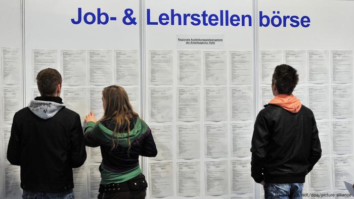 Jóvenes mirando ofertas de trabajo en una oficina de empleo.