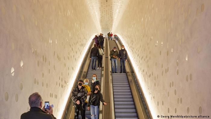 People stand on Western Europe's longest escalator as a man takes a photo