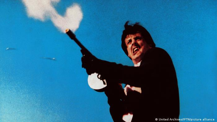 Film still 'Death Race 2000': Sylvester Stallone shooting a machine gun.