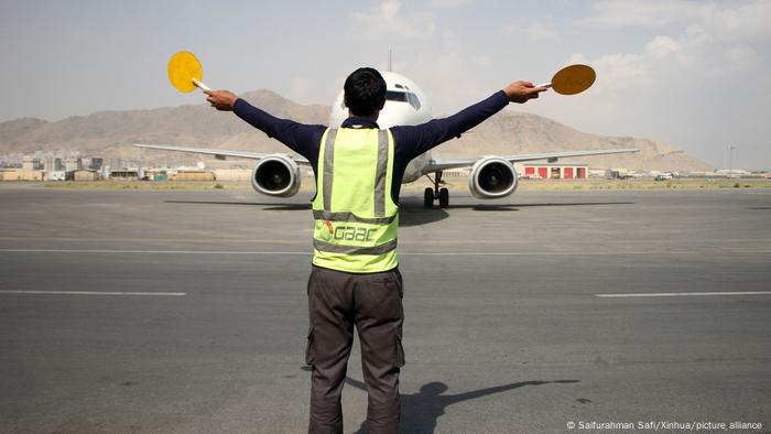 A member of the ground crew gives signals to the pilot of a plane at Kabul International Airport in Kabul, capital of Afghanistan