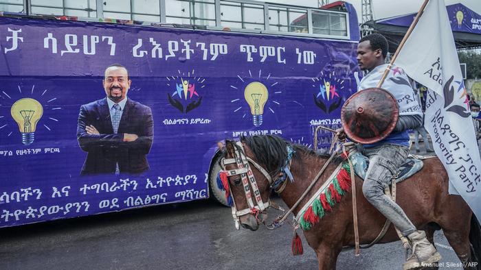 Ein Reiter auf einem Pferd hält eine Fahne von Abiy Ahmeds Partei PP während er hinter einem Wahlkampfbus herreitet. Ein Reiter auf einem Pferd hält eine Fahne von Abiy Ahmeds Partei PP während er hinter einem Wahlkampfbus herreitet.