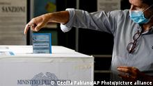 A man casts his ballots at a polling station, in Rome, Sunday, Oct. 3, 2021. Millions of people in Italy started voting Sunday for new mayors, including in Rome and Milan, in an election widely seen as a test of political alliances before nationwide balloting just over a year away. (Cecilia Fabiano/LaPresse via AP)