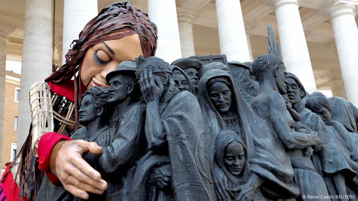 Little Amal hugging Angels Unawares, a bronze statue at St. Peter's Square by Timothy Schmalz