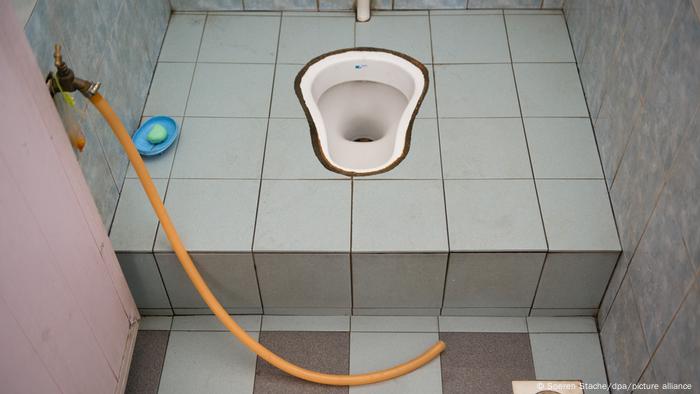 Tiled squatting toilet and a hose 