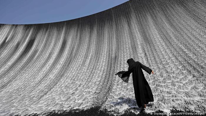 Žena u podnožju jedne od najvećih atrakcija u Dubaiju, na svetskoj izložbi EXPO 2020. Voda se sliva niz zakrivljene zidove visoke 13 metara i to u ritmu muzike koja je specijalno komponovana za EXPO. Ali pravi spektakl događa se noću kada voda, prkoseći gravitaciji, počinje da teče uz zidove.