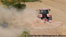 Ein Landwirt bearbeitet mit Hilfe eines Traktors ein Feld und wirbelt dabei eine große Staubwolke auf. Deutschland, Hohenhorn 17.08.2020 