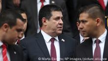 In this Aug. 15, 2018 photo, flanked by his security detail, Paraguay's outgoing President Horacio Cartes exits Congress leaving the presidential inauguration ceremony before it finished, in Asuncion, Paraguay. Cartes has been unhappy that incoming President Abdo Benitez has failed to back his effort to take an elected seat in the Senate. (AP Photo/Marta Escurra)