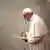 Papa Francisco lê um texto em frente a um microfone no Vaticano.