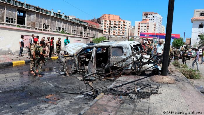Співробітники служби безпеки стоять серед уламків автівки, що вибухнула у Адені, забравши життя шістьох людей