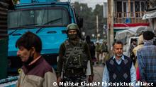 An Indian paramilitary soldier guards as a Kashmiris walk at a busy market in Srinagar, Indian controlled Kashmir, Monday, Oct. 11, 2021. The government forces have beefed up security in the region’s main city following a string of targeted killings last week. (AP Photo/Mukhtar Khan)