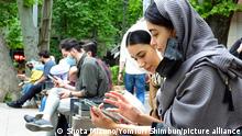 Women use their smartphones at a park in Tehran, Iran on April 24, 2021. The Iranian public is able to use Clubhouse, however Facebook and Twitter are still banned in Iran.( The Yomiuri Shimbun via AP Images )