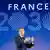 Emmanuel Macron speaking in front of 2030 sign