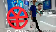 A visitor passes by a logo for the e-CNY, a digital version of the Chinese Yuan, displayed during a trade fair in Beijing, China, Sunday, Sept. 5, 2021. China's central bank on Friday, Sept. 24, 2021 declared all transactions involving Bitcoin and other virtual currencies illegal, stepping up a campaign to block use of unofficial digital money. It is developing an electronic version of the country's yuan for cashless transactions that can be tracked and controlled by Beijing. (AP Photo/Ng Han Guan)