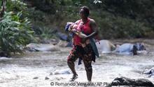 A migrant woman crosses the Acandi River with a child in her arms, in Acandi, Colombia, Wednesday, Sept. 15, 2021. A group of migrants, following a well-beaten, multi-nation journey towards the U.S., will continue their journey through a jungle known as the Darien Gap. (AP Photo/Fernando Vergara)