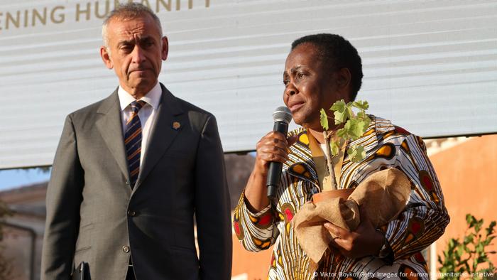 Julienne Lusenge delivers her acceptance award holding a plant with Lord Ara Darzi looking on