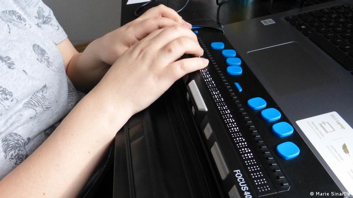 Eine blinde Studentin erstastet eine Formel auf der Braillezeile